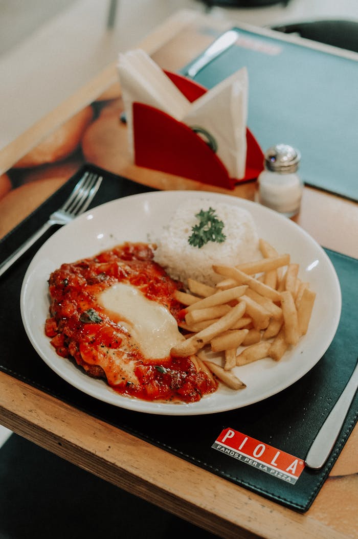 Savory chicken parmesan served with crispy fries and rice in a restaurant setting.
