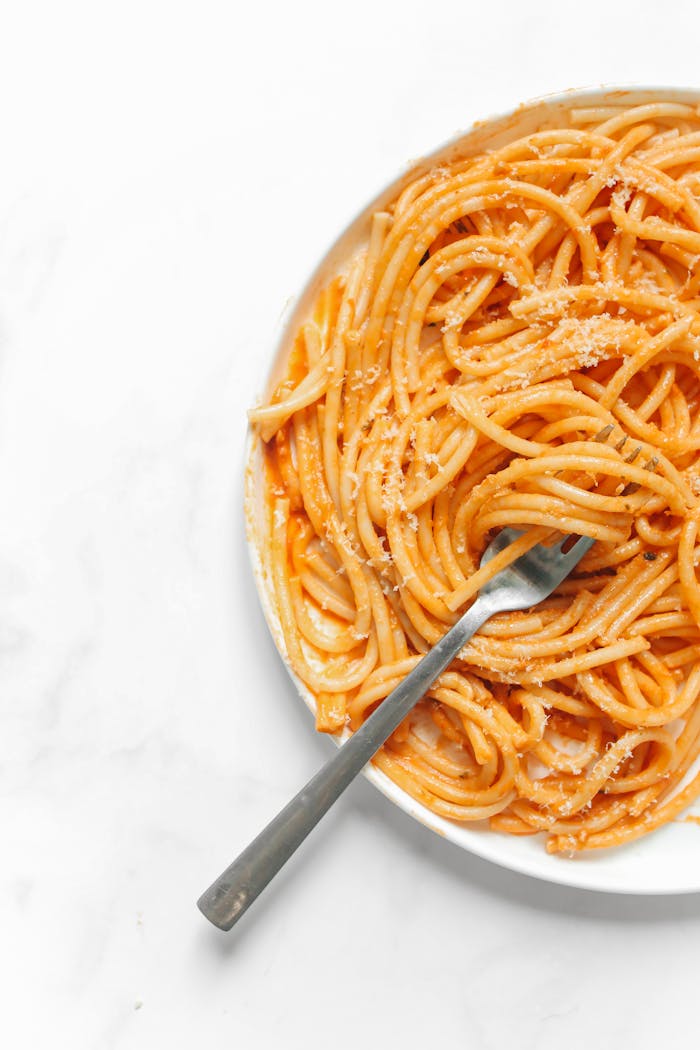 Close-up of a savory plate of spaghetti in tomato sauce on a white background.
